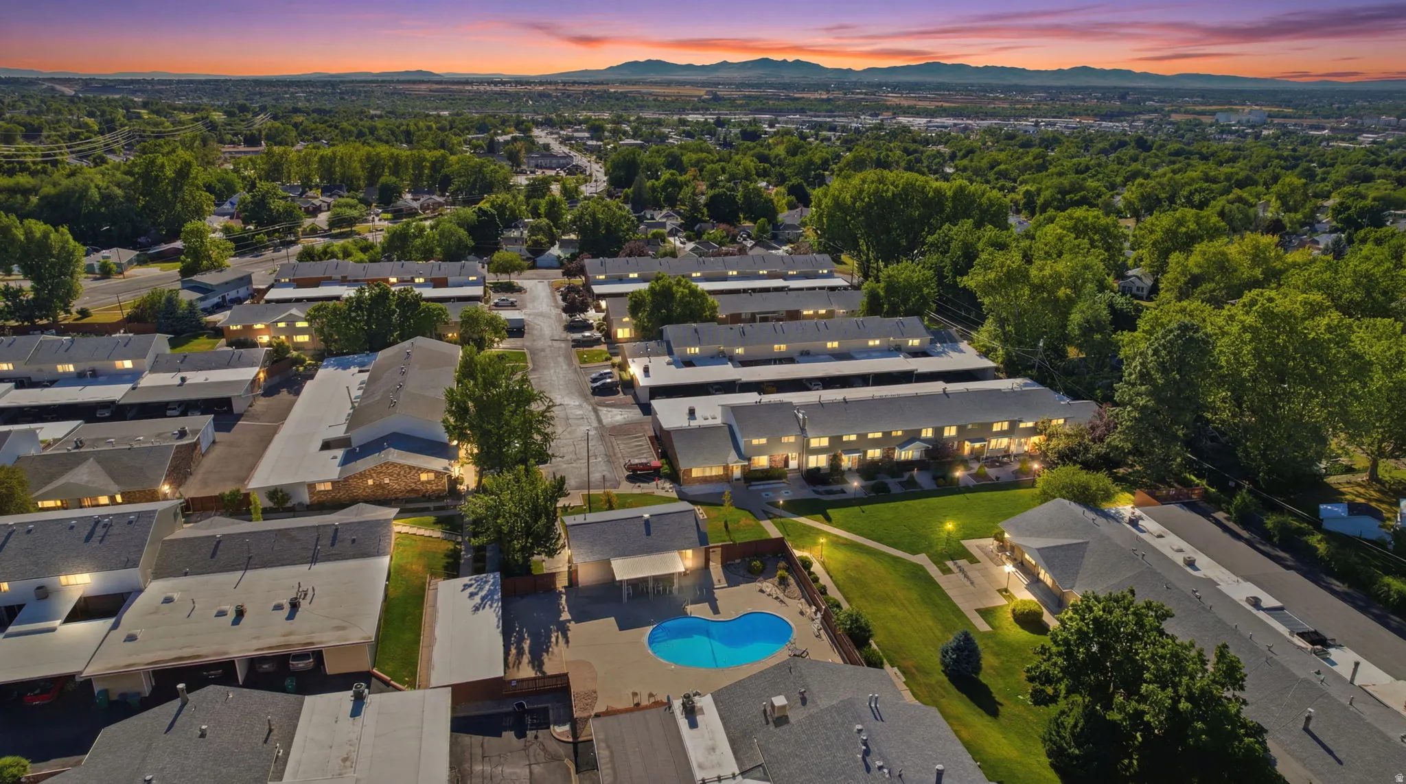 Expansive property featuring multiple residential buildings, mature trees, and a central swimming pool