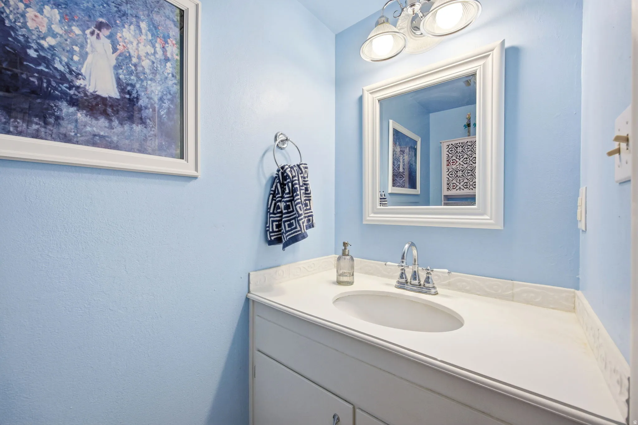 Light blue wall color complementing a white vanity with an integrated sink and countertop