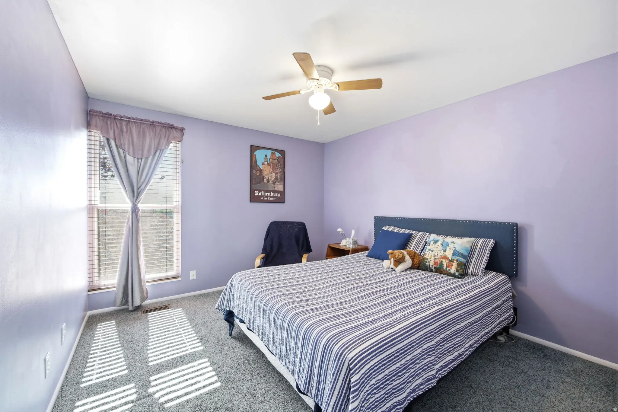 Bedroom featuring a ceiling fan with light fixture, window with blinds and drapes, and carpeted flooring