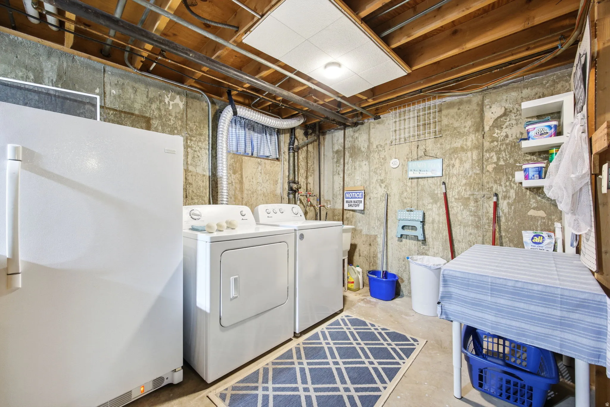 Dedicated laundry area featuring a washer and dryer, exposed concrete walls, and open ceiling joists