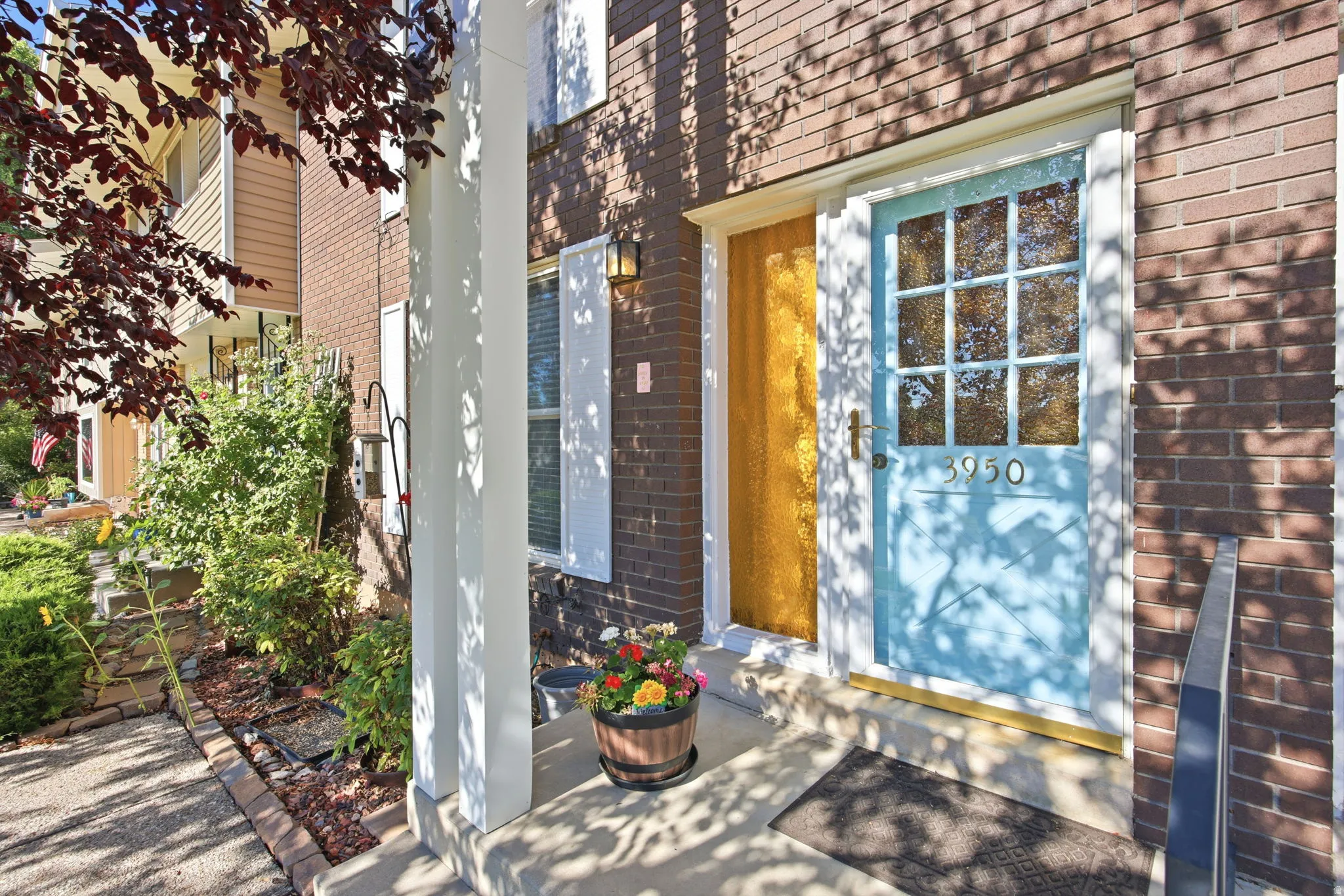 Brick exterior facade featuring a light blue front door with glass panels, a textured glass sidelight, and a white shuttered window