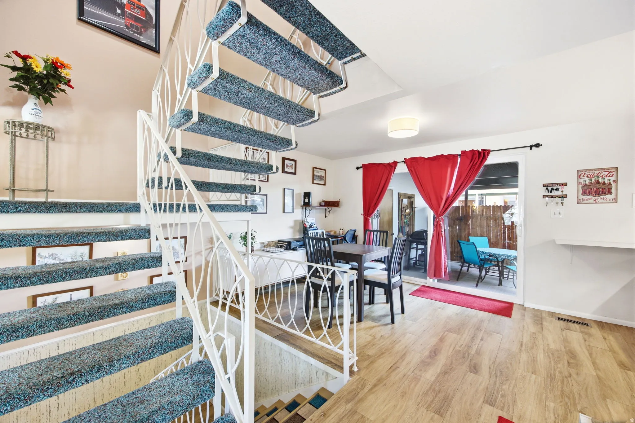 Curved staircase with decorative metal railing and carpeted treads, complemented by wood-finish flooring