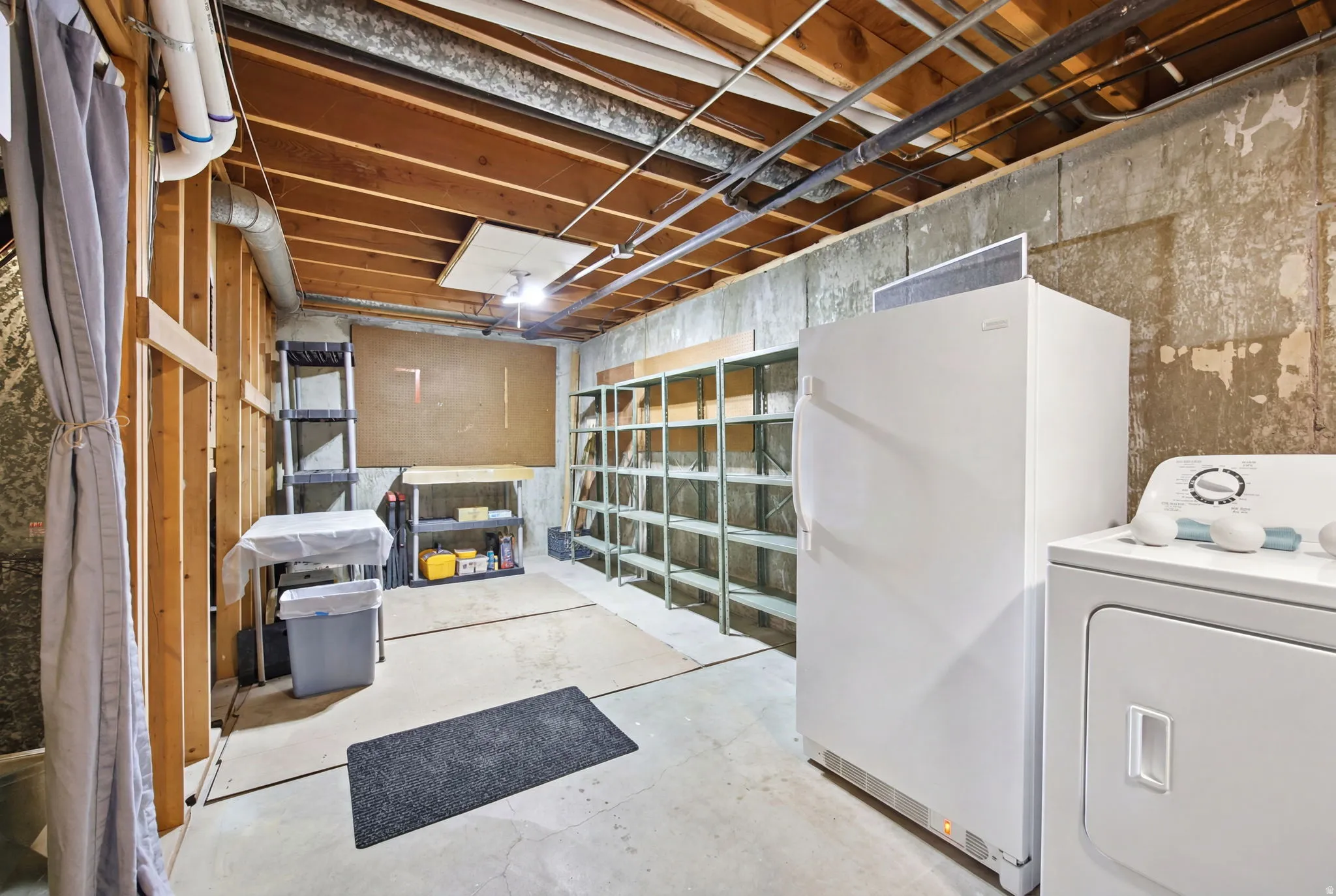 Unfinished basement area with exposed ceiling joists and concrete flooring