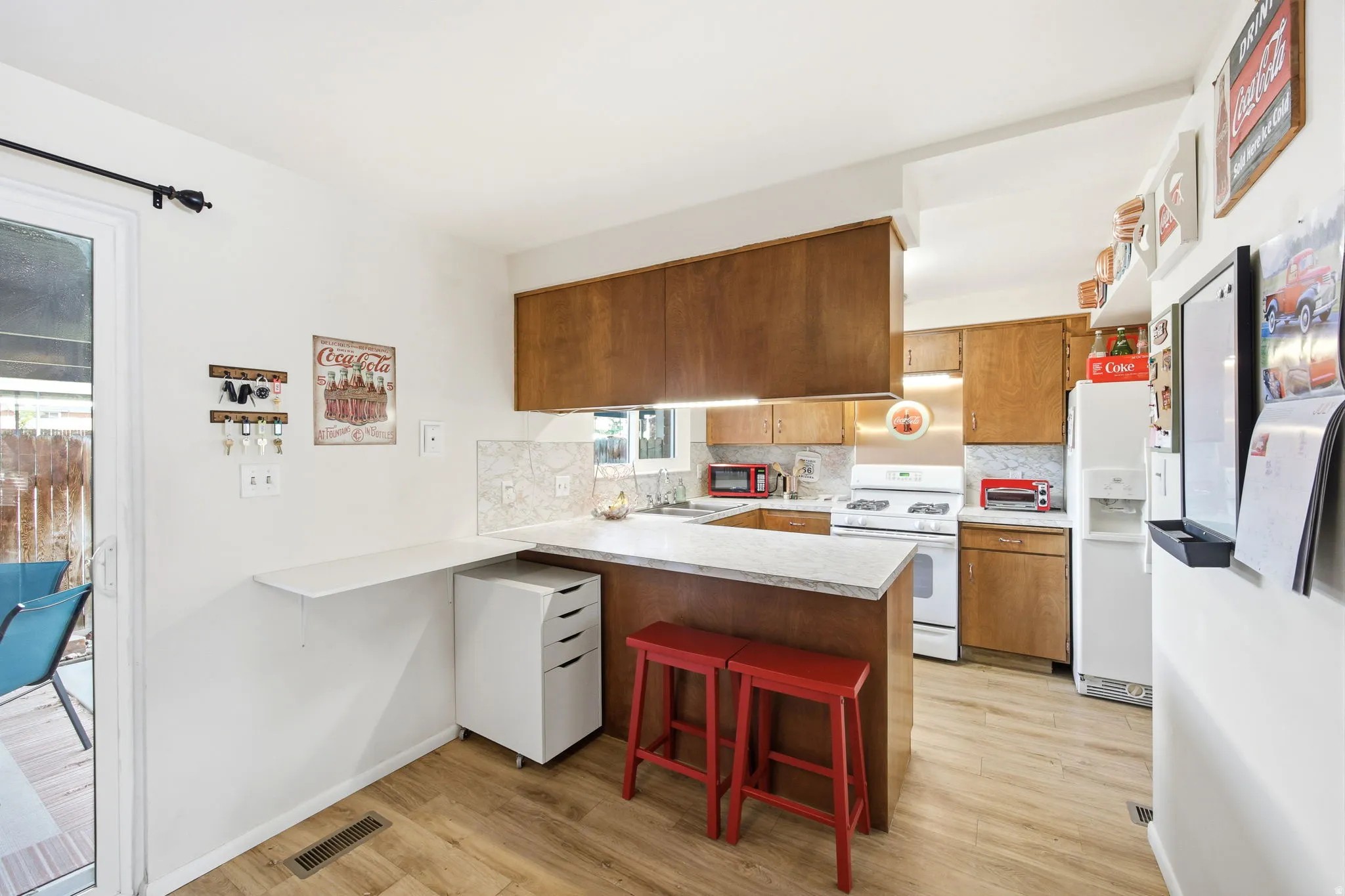 Kitchen featuring wood-finish flooring, light-toned countertops, and a white tile backsplash