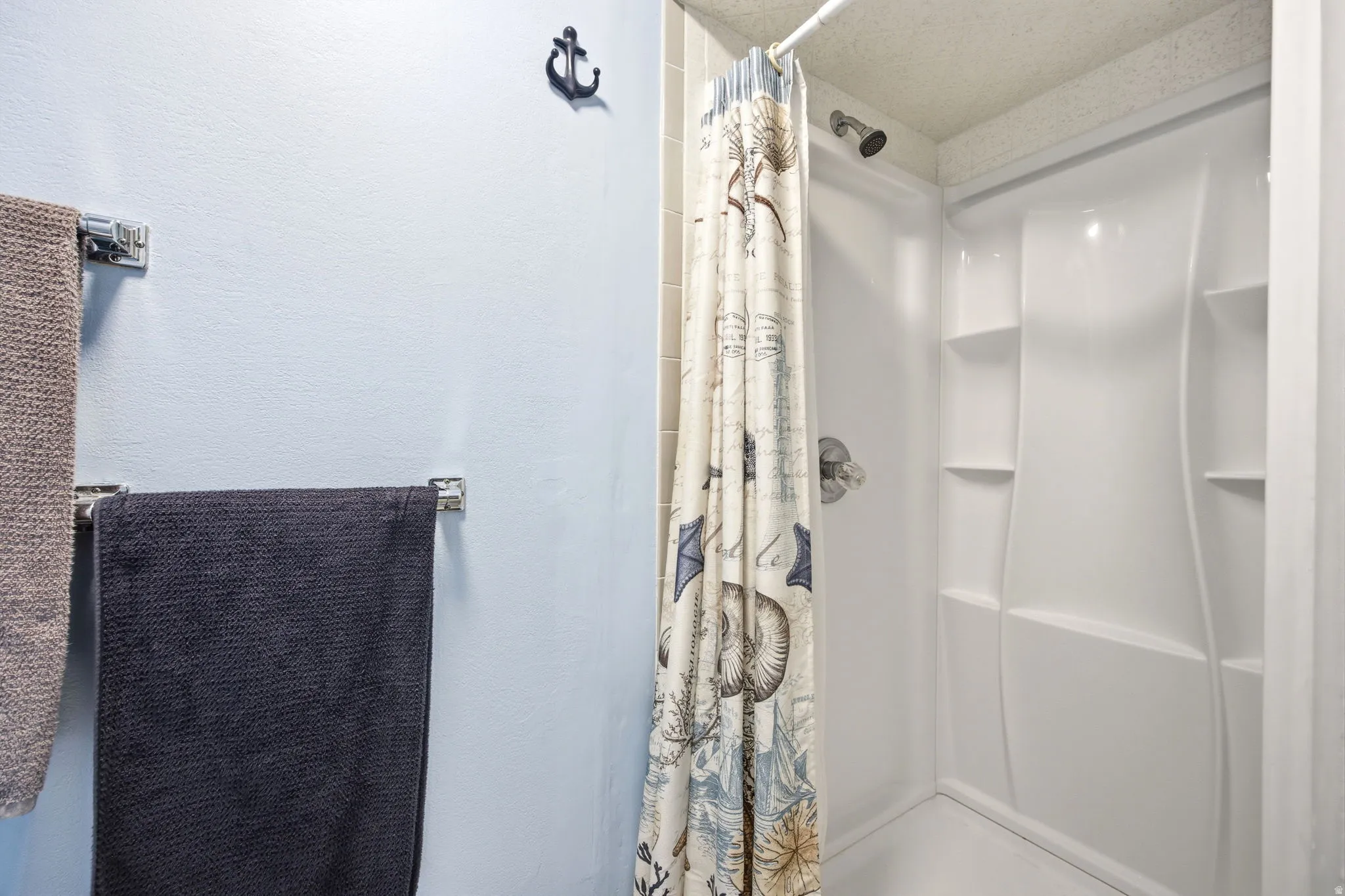 Bright white shower enclosure featuring a fixed shower head and built-in shelving