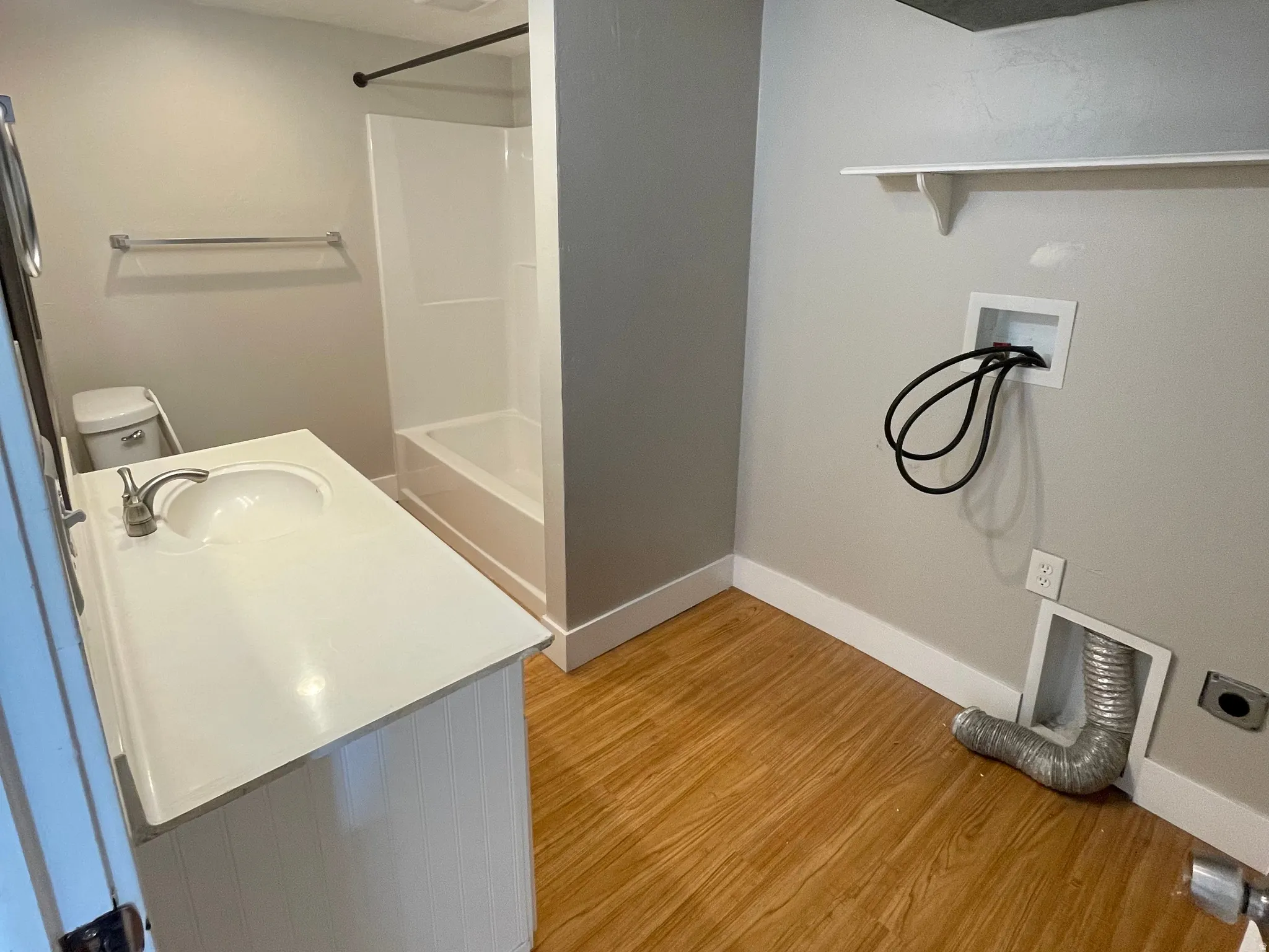 Bathroom featuring a white vanity with integrated sink, chrome faucet, toilet, and a white tub/shower combination