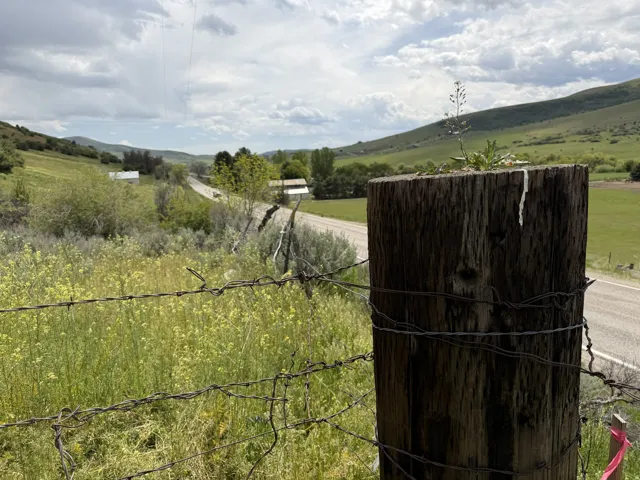 Expansive rural landscape featuring rolling green hills and distant structures