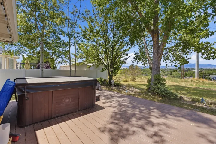 Spacious outdoor deck featuring a hot tub, composite decking, and mature trees