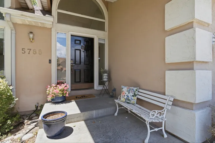 Front entry featuring a paneled black door with transom window and sidelights, stucco exterior, decorative wall sconce, and concrete porch