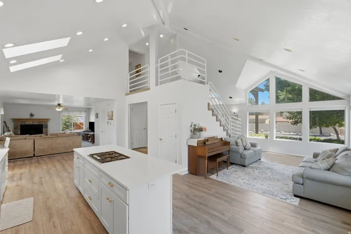 Spacious interior featuring a vaulted ceiling with skylights, wood-finish flooring, and a contemporary open-tread staircase with white railings