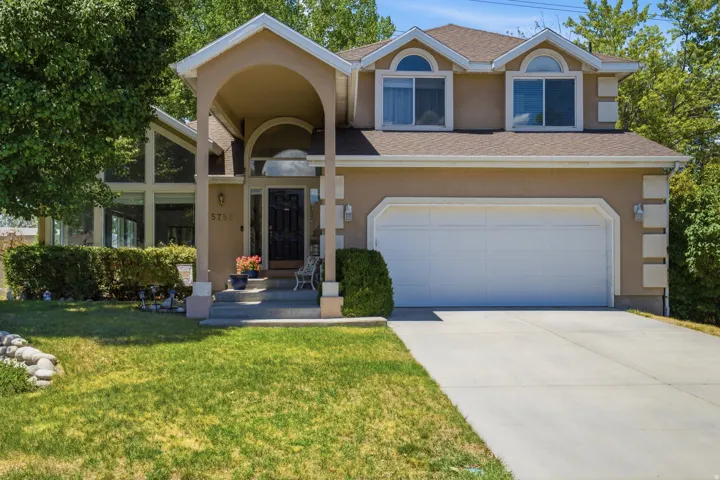 Stucco exterior with an arched entryway, gabled roofline, and an integrated two-car garage