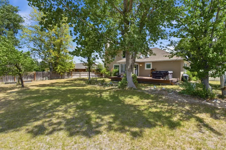 Expansive backyard featuring a large wood deck, mature trees, and a full privacy fence