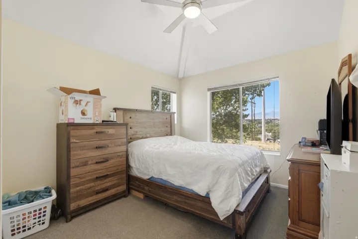 This bedroom offers vaulted ceilings, soft carpet flooring, and a ceiling fan with integrated lighting
