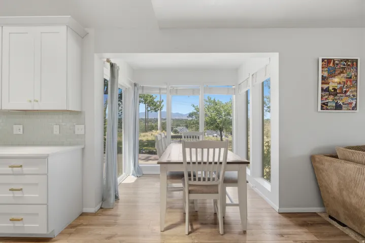 Dining area with expansive window wall, featuring a sliding glass door and wood-finish flooring