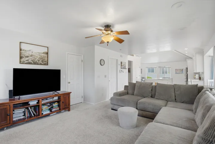 Carpeted living area featuring a ceiling fan with light, recessed lighting, and a white interior door