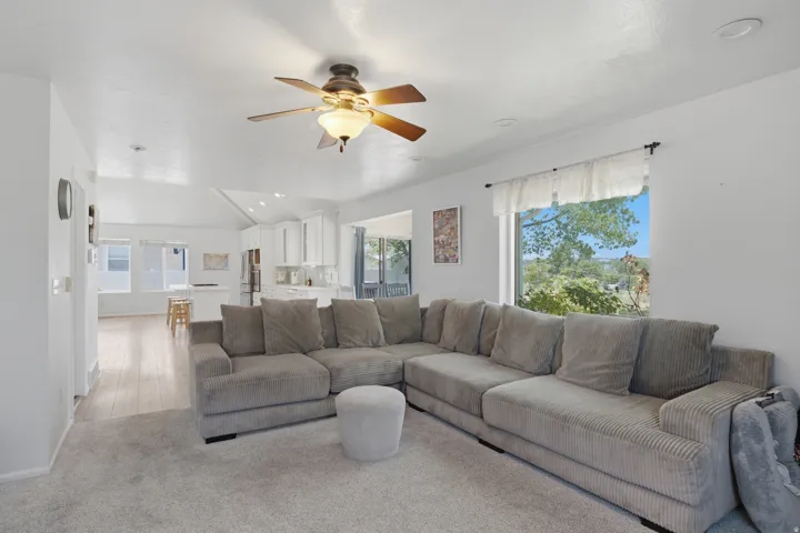 Open-concept living space featuring light-toned wood-finish flooring and light-toned carpeting