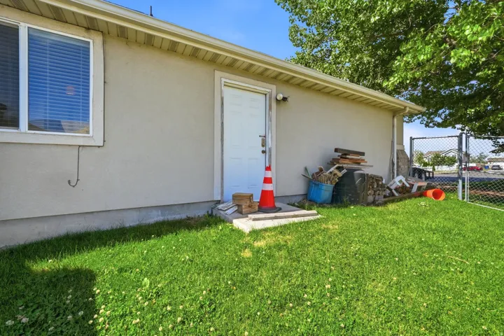 Manicured lawn area with a stucco exterior, white trim, and a chain-link fence