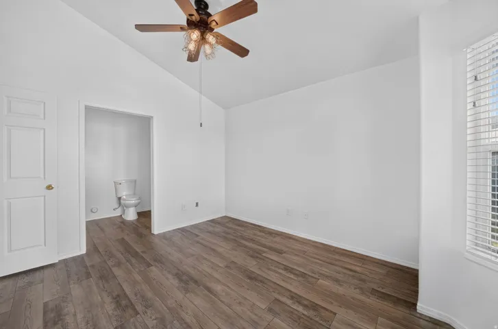 Room with wood-finish flooring, white walls, and a ceiling fan with integrated lighting
