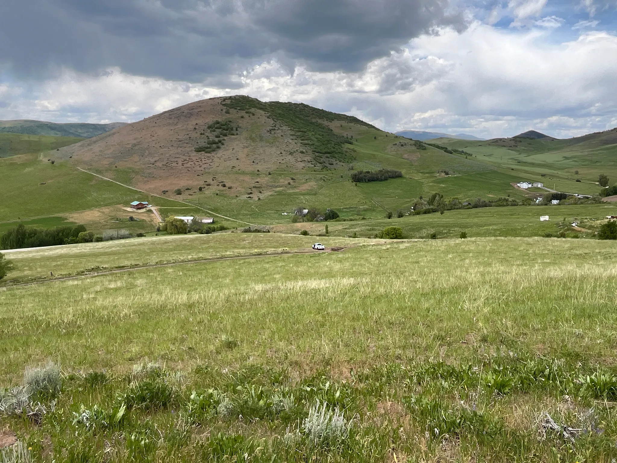 Expansive green landscape with rolling hills and distant structures