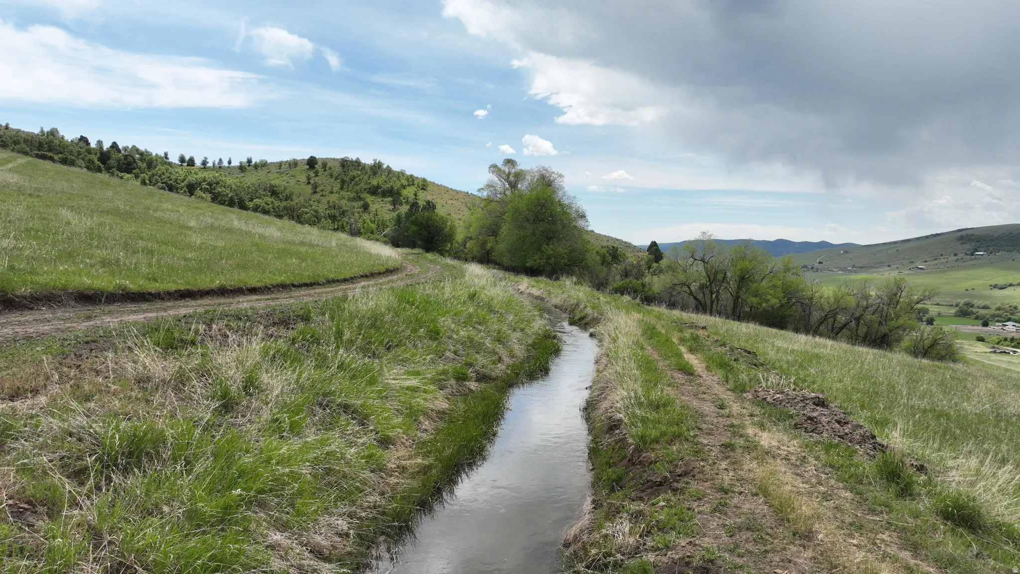 Natural water channel with surrounding green hillsides and distant valley scenery