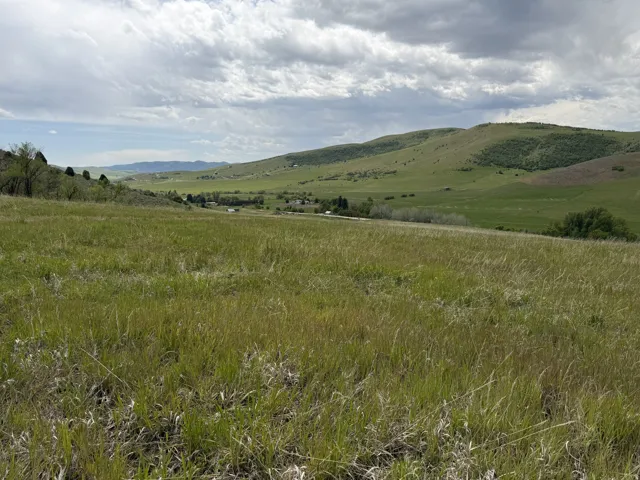 Expansive grassy landscape with rolling hills and distant structures