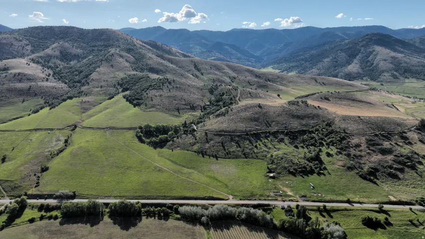 Expansive rural landscape featuring rolling green hills and distant mountains