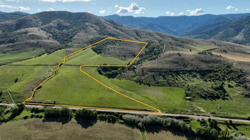 Expansive land parcel featuring varied topography, including rolling green hillsides and wooded sections