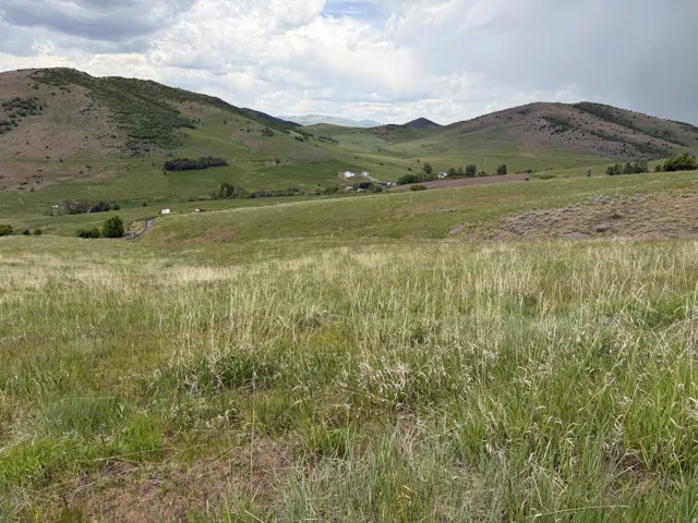 Expansive land parcel featuring rolling hills, abundant green vegetation, and distant mountain backdrops
