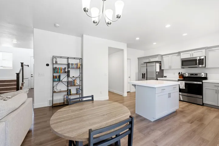 Open concept living space featuring a modern kitchen with light gray cabinetry, stainless steel appliances, and a central island with a white countertop