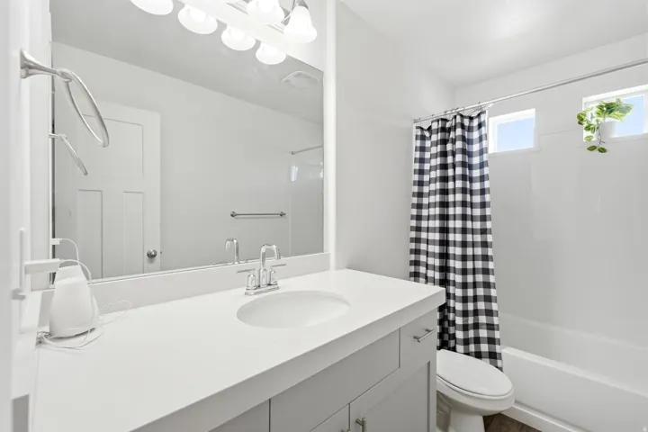 Contemporary bathroom featuring a white single-sink vanity with a light-colored countertop, chrome faucet, and a large mirror
