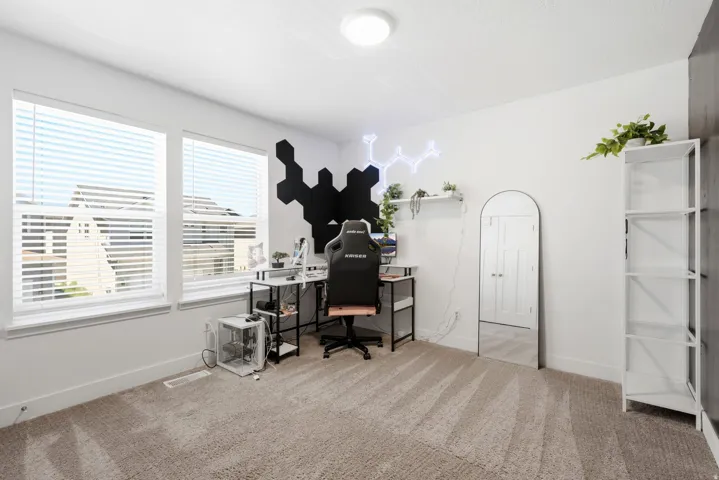 Expansive room featuring two large windows with blinds, light-toned carpet flooring, and a white ceiling with a flush-mount light fixture