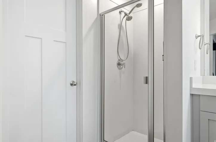 Glass-enclosed shower with brushed nickel fixtures and a dual shower head