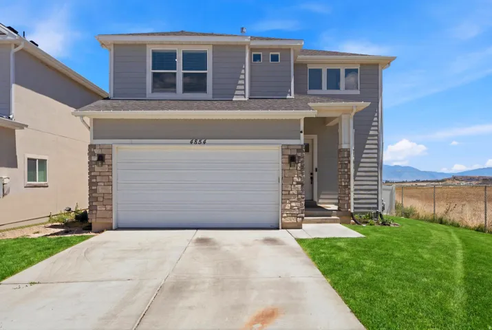 Two-story residence featuring light gray siding with stone veneer accents