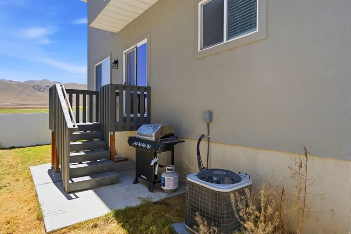 Rear exterior with a concrete patio, Trex stairs, and a grey stucco finish