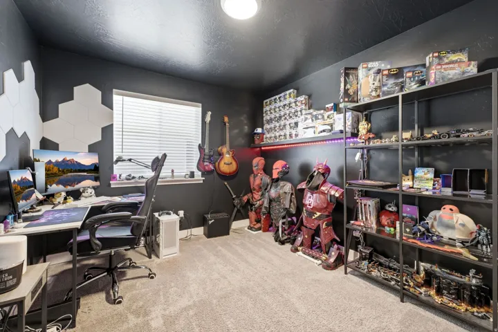 Carpeted room featuring a single window with horizontal blinds, hexagonal wall decor, and a shelving unit