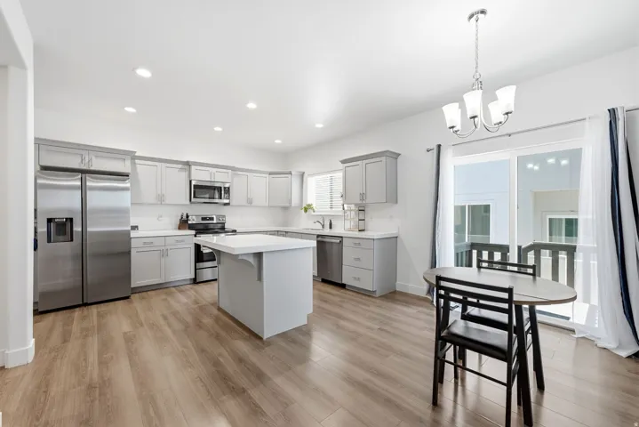 Modern kitchen featuring stainless steel appliances, light gray cabinetry, white countertops, and wood-finish flooring