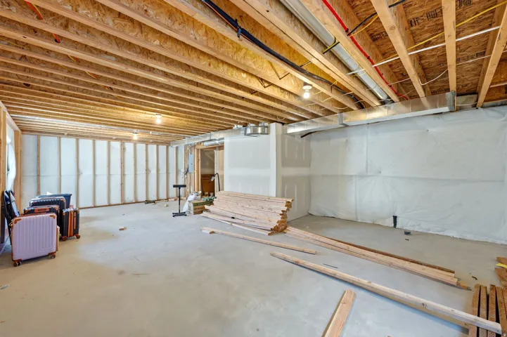 Unfinished basement featuring exposed wood ceiling joists and concrete flooring
