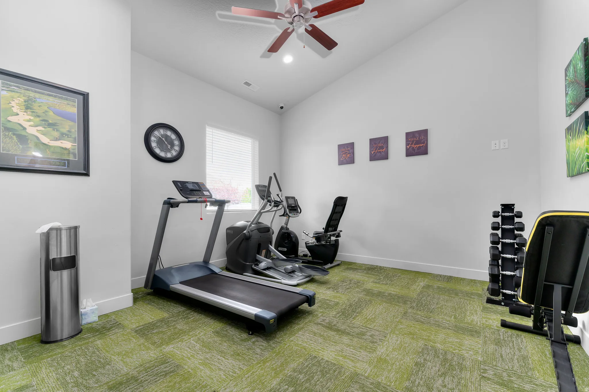 Recreational space with green patterned carpet, white walls, and a ceiling fan