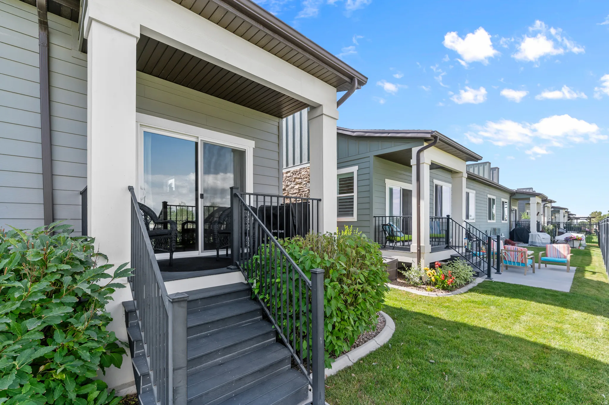 HOME EXTERIOR - REAR Private patio with sliding glass door entry, composite decking, and black metal railings