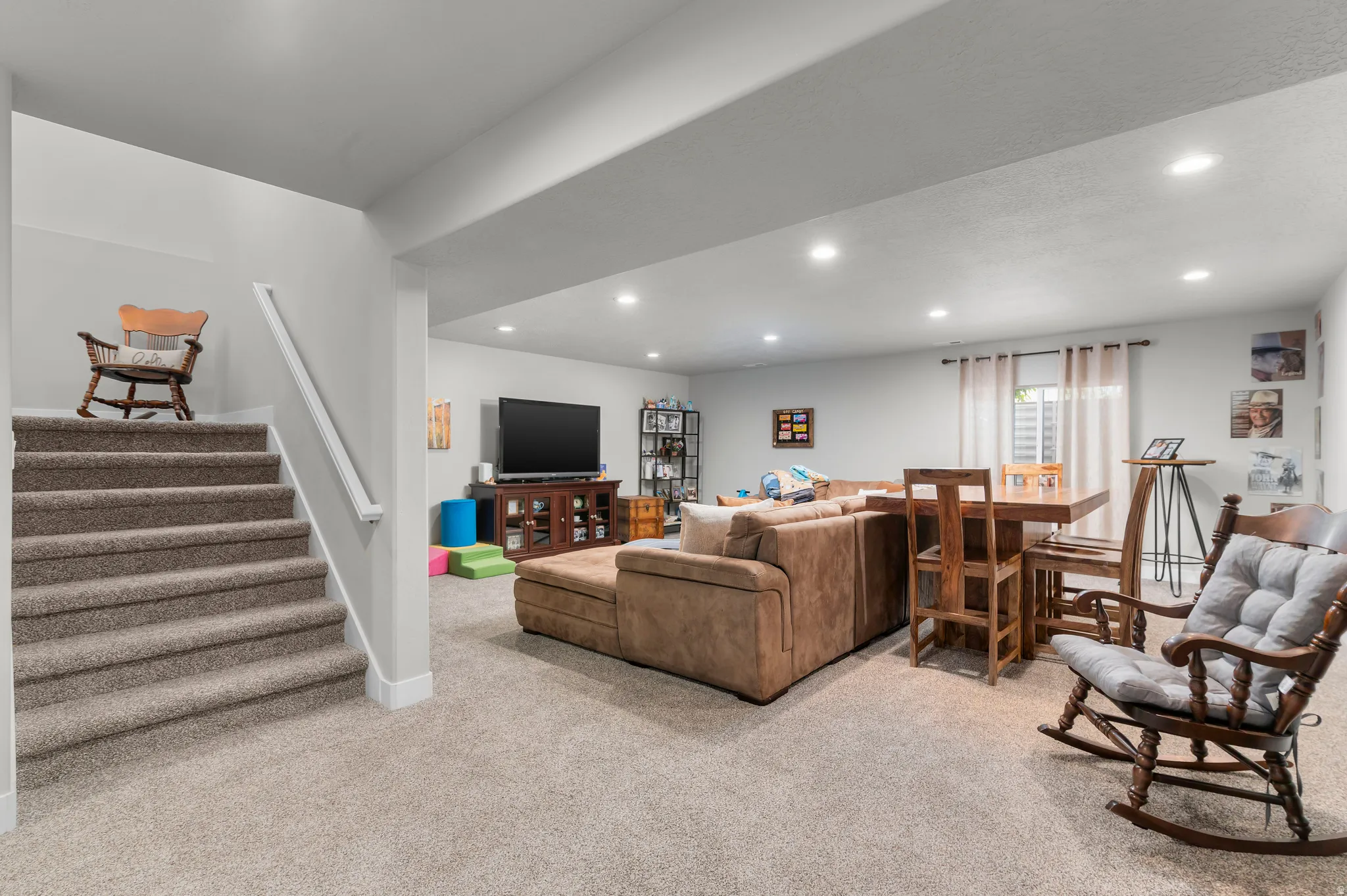 Carpeted lower-level room featuring recessed lighting, a window with blinds, and white trim