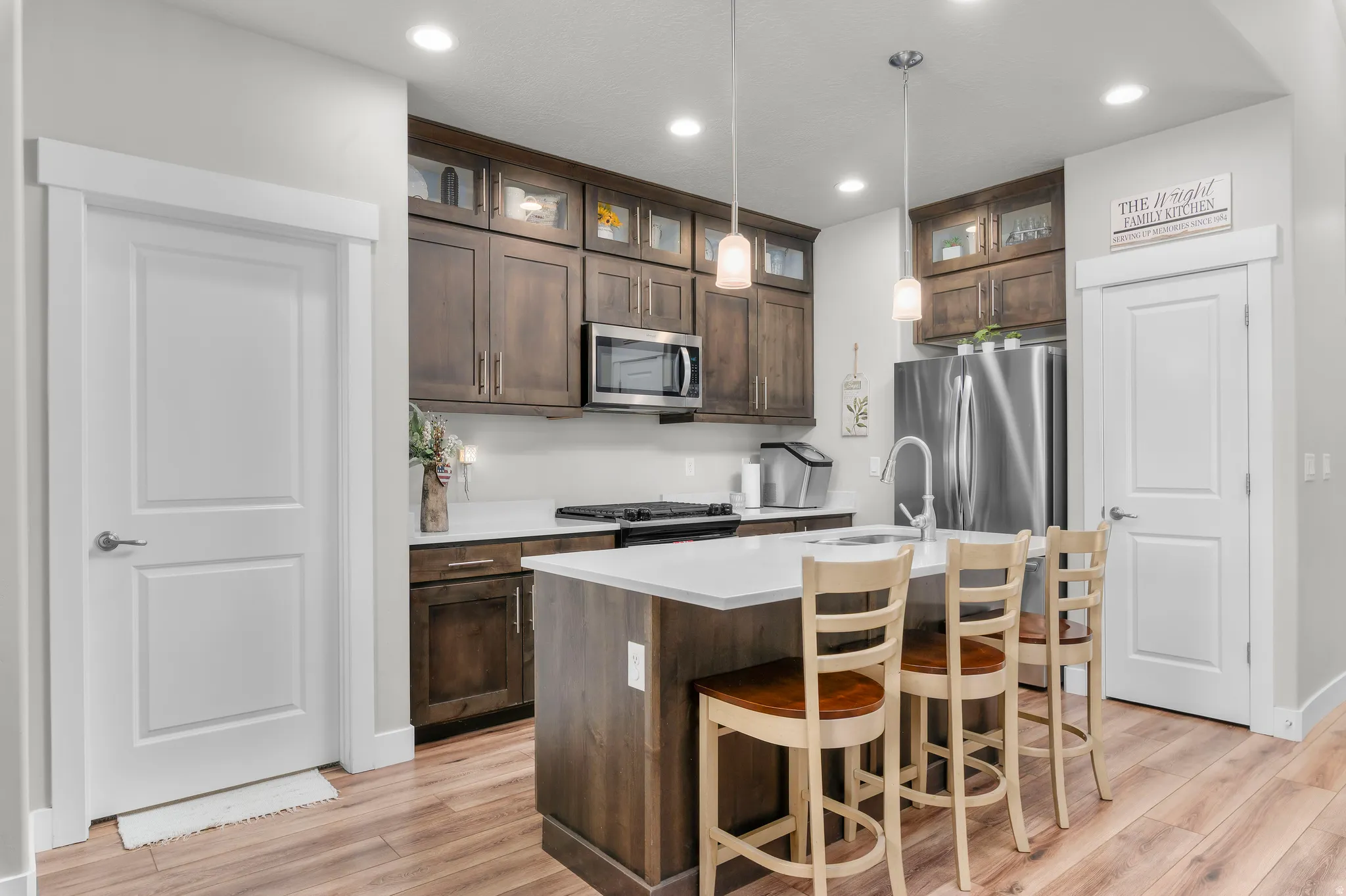 Modern kitchen featuring wood-finish flooring, white countertops, and dark wood cabinetry