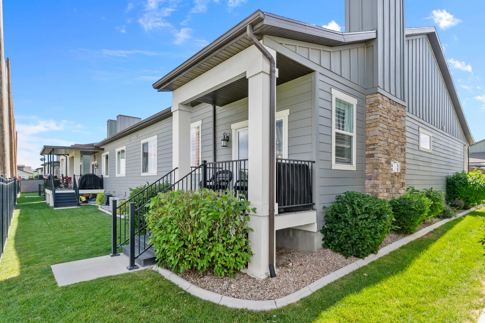 HOME EXTERIOR - REARExterior featuring gray horizontal siding, a stone veneer accent, and a covered porch with black railings