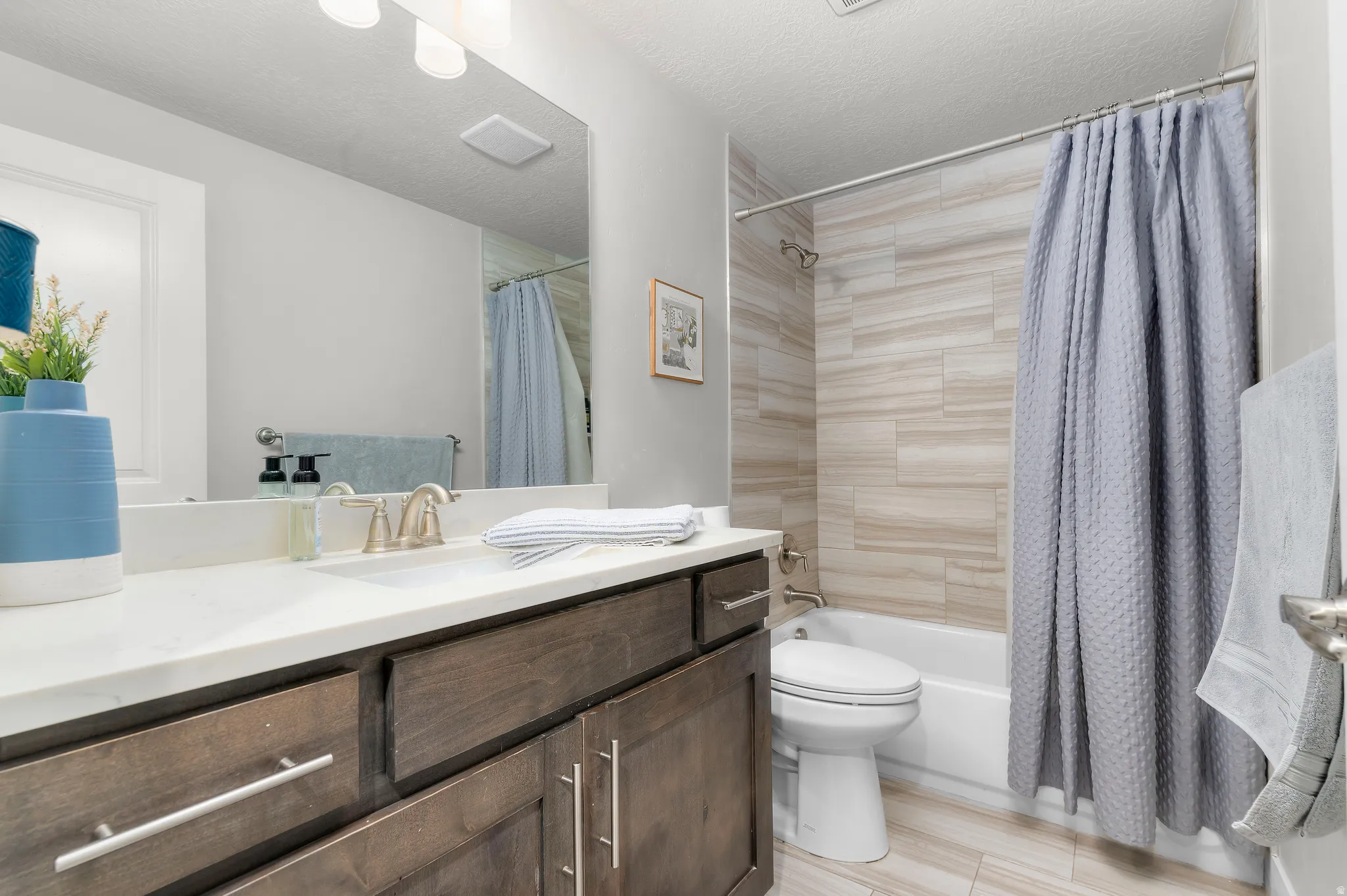 Bathroom featuring a wood-finish vanity with a white countertop and undermount sink, brushed nickel faucet, and a large wall-mounted mirror