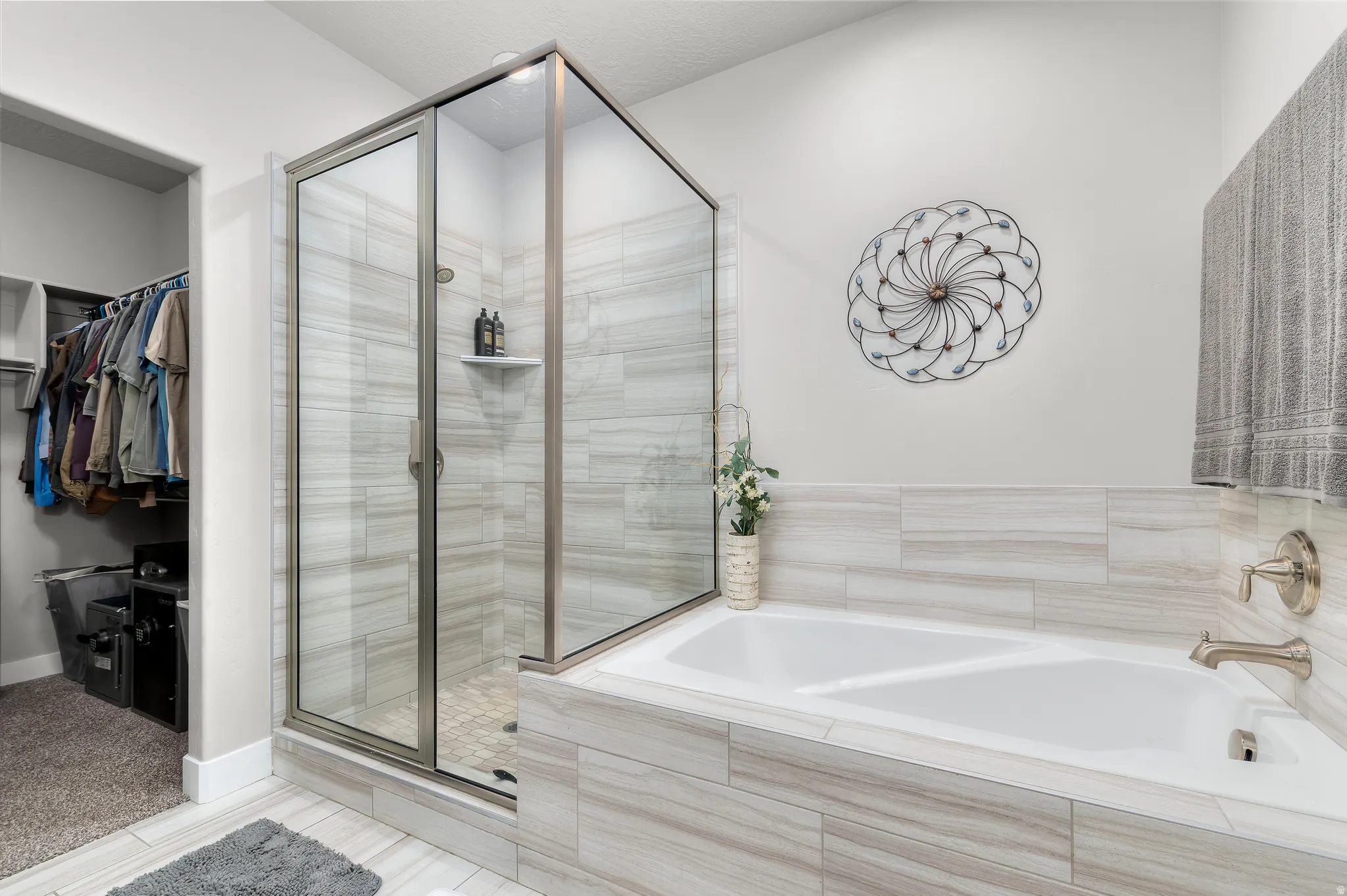 Spacious bathroom featuring a glass-enclosed shower with tile surround, a built-in soaking tub with tile surround, brushed nickel fixtures, and light-toned tile flooring