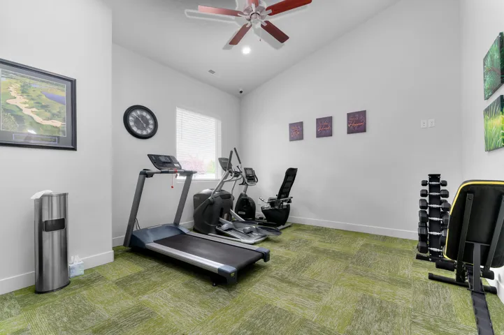 Recreational space with green patterned carpet, white walls, and a ceiling fan