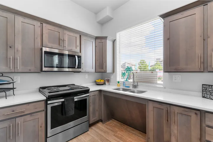 Kitchen featuring wood-finish cabinetry, stainless steel appliances, white countertops, and wood-finish flooring