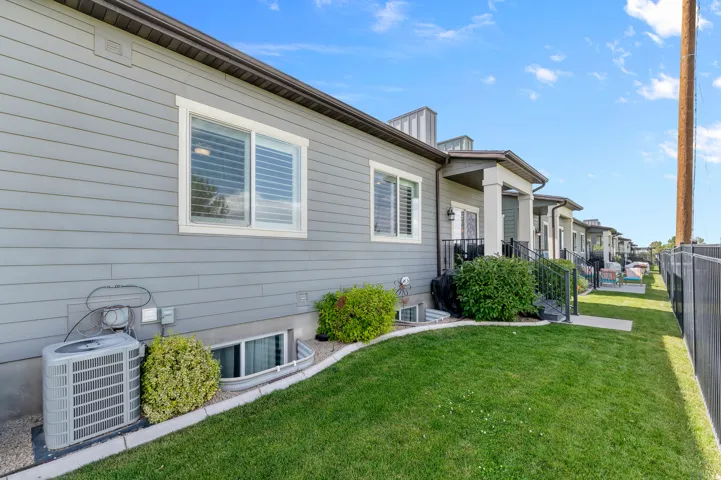 HOME EXTERIOR - REAR Manicured lawn extending along the side of the property, bordered by a dark metal fence