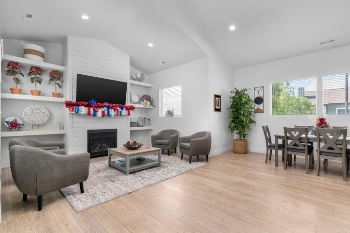 Open-concept living space featuring wood-finish flooring, a contemporary fireplace with horizontal shiplap detailing, and built-in shelving
