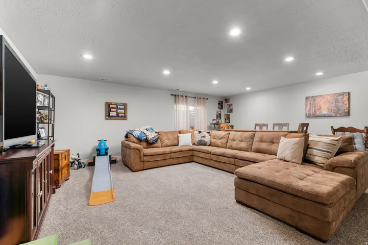 Spacious carpeted room featuring recessed lighting, light gray walls, and a large window with privacy blinds