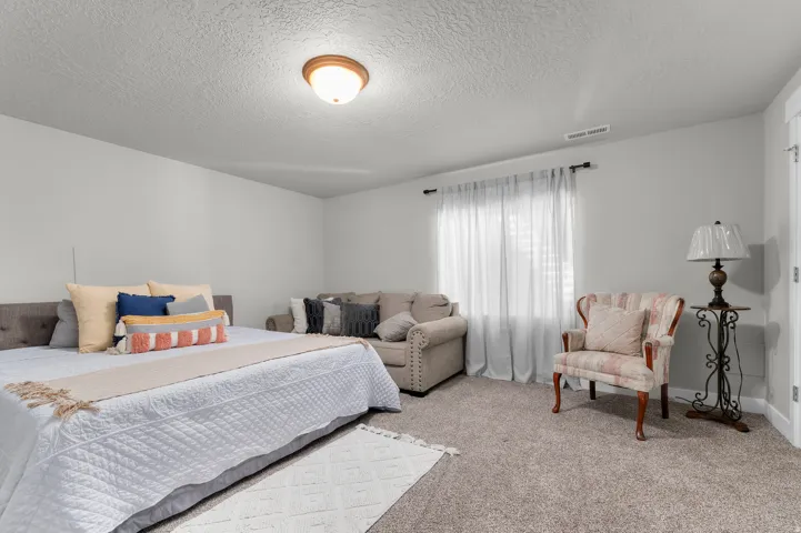 Carpeted room with light neutral walls and a window with white sheer curtains
